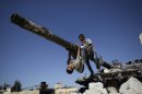 A boy looks back while he and another boy play on a Syrian military tank, destroyed during fighting with the Rebels, in the Syrian town of Azaz, on the outskirts of Aleppo, Sunday, Sept. 2, 2012. (AP Photo/Muhammed Muheisen)