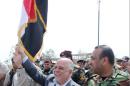 In this image posted on the official Facebook account of Iraq's Prime Minister Haider al-Abadi shows the premier carrying the national flag as he walks with Iraqi security forces in Tikrit, Iraq, Wednesday, April 1, 2015. Iraqi security forces battled the last remaining pockets of Islamic State militants in Tikrit on Wednesday before the defense minister declared a 'magnificent victory' over the Islamic State group in Tikrit. (AP Photo/Iraq Prime Minister's office)