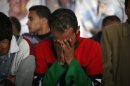 A Libyan man, wearing the colors of the pre-Gadhafi flag, weeps for his brother at a funeral in Benghazi, Libya, Monday, March 5, 2012 for victims buried in a mass grave. Thousands of mourners gathered Monday in the eastern Libyan city of Benghazi to bury 155 bodies unearthed from a mass grave of people were killed during last year's civil war. It was the largest grave yet to be discovered from the conflict that began as a popular uprising and ended with the capture and killing of Libyan leader Moammar Gadhafi last October.(AP Photo/Manu Brabo)