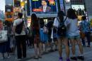 People watch Japan's Prime Minister Abe on screen as he gives statement in Tokyo