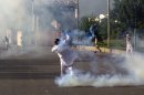 A Pakistani protester tosses a tear gas canister back at police behind containers blocking the road to the diplomatic enclave in Islamabad, Pakistan, Friday, Sept. 21, 2012. Pakistani police opened fire on rioters who were torching a cinema during a protest against an anti-Islam film Friday, and security forces clashed with demonstrators in several other cities in Pakistan on a holiday declared by the government so people could rally against the video. Thousands of people protested in several other countries, some of them burning American flags and effigies of President Barack Obama. (AP Photo/B.K. Bangash)