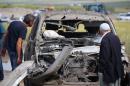 People look at a damaged car at the site of last night's explosion near the Kurdish-dominated southeastern city of Diyarbakir