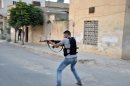 In this Sunday, 22 July, 2012 photo a Syrian rebel fires his weapon during clashes with Syrian troops in Idlib, Syria. (AP Photo/Fadi Zaidan)