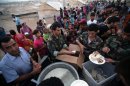 Syrian-Kurdish refugee families queue to get food at the Quru Gusik refugee camp on August 27, 2013