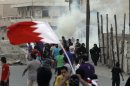 Bahraini anti-government protesters, one carrying a national flag, react to tear gas fired by riot police Saturday, April 21, 2012, in Diraz, Bahrain, west of the capital of Manama. Bahraini opposition groups claimed Saturday that a man was killed during clashes with security forces, threatening to sharply escalate the Gulf nation's unrest as officials struggle under the world's spotlight as hosts of the Formula One Grand Prix. Authorities opened an investigation in a bid to diffuse tensions. (AP Photo/Hasan Jamali)