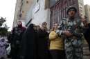 Soldier stands guard as women queue outside a polling center to vote in referendum on Egypt's new constitution in Cairo