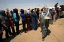 Syrian-Kurdish refugee families queue to get food at the Quru Gusik refugee camp, 20 kilometres east of Arbil, the capital of the autonomous Kurdish region of northern Iraq, on August 29, 2013