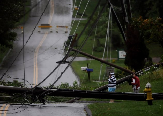 Residents on Foster Street in South Windsor, Conn., look over the mess of wires and down utility poles that were brought down during Irene, the hurricane that weakened to a tropical storm, Sunday, Aug