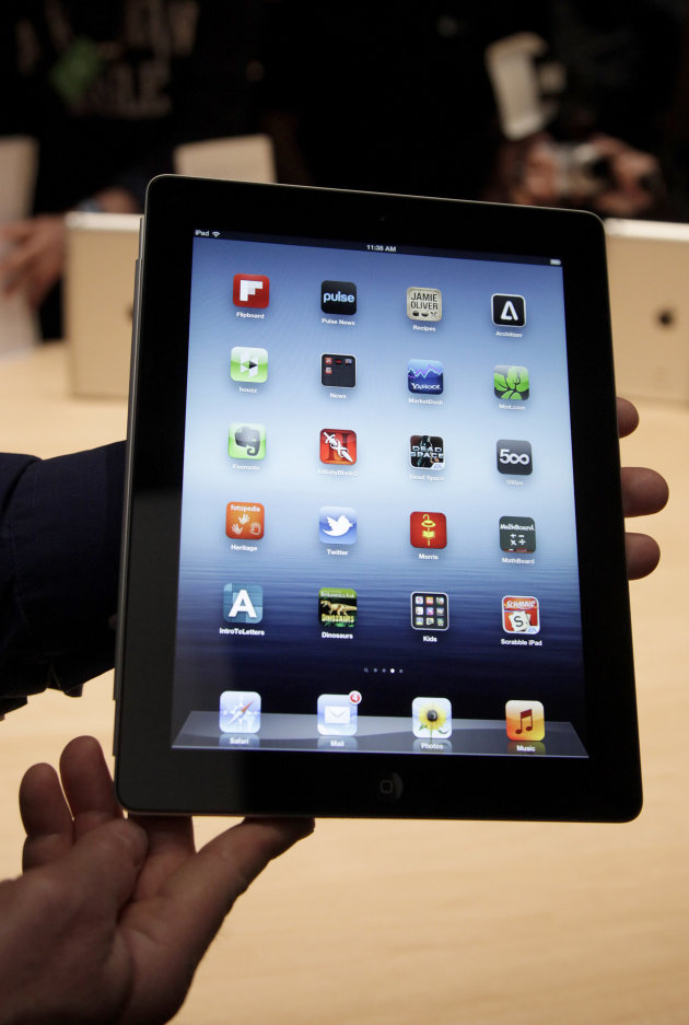 FILE - In this March 7, 2012 file photo, an Associated Press reporter holds up the new iPad during an event in San Francisco. Rumors of a smaller iPad, or “iPad mini” have percolated ever since the fi