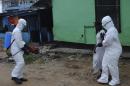 Health workers spray bleach solution on a woman suspected of having contracted the Ebola virus in Monrovia