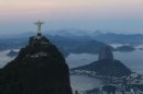 FILE - In this May 10, 2012 file photo, the Christ the Redeemer statue stands back dropped by Sugar Loaf mountain, right, as the sun sets in Rio de Janeiro, Brazil. The Olympic flame goes out in London on Sunday, Aug. 12, 2012, and all eyes turn to Rio, which in 2016 will become the first South American city to host the Games. (AP Photo/Felipe Dana, File)