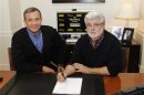 Walt Disney Company Chairman and CEO Iger and filmmaker and Chairman of the Board of Lucasfilm Ltd. Lucas sign documents at the Walt Disney Co. in Burbank