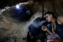 In this Monday, Sept. 30, 2013 photo, a Palestinian worker smokes a cigarette inside a smuggling tunnel along the border with Egypt in Rafah, southern Gaza Strip. Gaza's tunnel smugglers along the border with Egypt are mostly idle these days. Some rest on cots in the dank underground pathways, stretching out for a smoke. Others pass the time cleaning the small carts on wheels that are normally pulled through the tunnels carrying cement or consumer goods from Egypt. Since the summer, Egypt's military has tried to destroy or seal off most of the smuggling tunnels under the Gaza-Egypt border, a consequence of the heightened tensions between Cairo and the Hamas government in Gaza. (AP Photo/Hatem Moussa)
