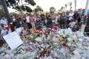 People gather around a makeshift memorial to pay tribute to the victims of an attack in the French Riviera city of Nice on July 15, 2016, a day after when a man rammed a truck through a crowd celebrating Bastille Day, killing at least 84 people