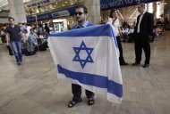An activist holds an Israeli flag in protest against a pro-Palestinian campaign expected to arrive at Ben Gurion Airport near Tel Aviv, Israel, Sunday, April 15, 2012. Israel deployed hundreds of police Sunday at its main airport to detain activists flying in to protest the country's occupation of Palestinian areas, defying vigorous Israeli government efforts to block their arrival. (AP Photo/Tsafrir Abayov)