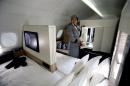 An Etihad Airways official stands inside a mock-up first class cabin, at a training facility in Abu Dhabi, United Arab Emirates, Sunday, May 4, 2014. Etihad Airways, a fast-growing Mideast carrier, laid out plans Sunday to offer passengers who find first-class seats a bit too tight a miniature suite featuring a closed-off bedroom, private bathroom and a dedicated butler. (AP Photo/Kamran Jebreili)