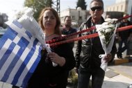 People holding flowers and a Greek flag stand near the local offices of far-right Golden Dawn party, following last night's shooting, in a northern suburb of Athens November 2, 2013. REUTERS/John Kolesidis