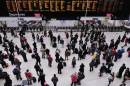 People wait with their luggage by the departure boards in Waterloo train station in central London December 24, 2013