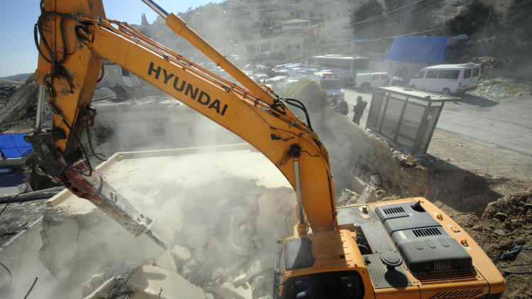 A bulldozer works on a Palestinian home demolished in East Jerusalem Wednesday, Feb. 5, 2014, Three Palestinian homes were demolished in the neighborhood, as the Israeli planners Wednesday gave final approval for 558 apartments in Jewish settlements in war-won east Jerusalem. (AP Photo/Mahmoud Illean)