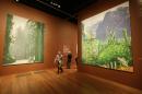 In this photo taken Thursday, Oct. 24, 2013, a man walks between a pair of 12-foot high views of Yosemite National Park, made by David Hockney using an iPad, at an exhibit in San Francisco. A sweeping new exhibit of Hockney's work, including about 150 iPad images, has opened in the deYoung Museum in Golden Gate Park, just a short trip for Silicon Valley techies who created both the hardware and software for this magnificent reinvention of fingerpainting. (AP Photo/Eric Risberg)