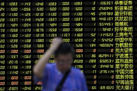 An investor stands in front of electronic board showing stock information at brokerage house in Shanghai