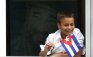 A Cuban boy with a portrait of Fidel Castro behind him watches Pope Benedict XVI's caravan make its way to the airport in Havana