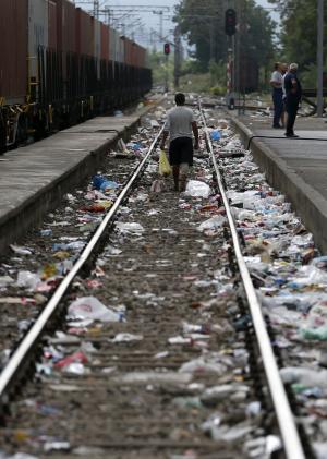 A man walks along the litter strewn  railway tracks at the railway station in the southern Macedonian town of Gevgelija, Thursday, Aug. 20, 2015. Macedonian  police  stepped up the security at the border with Greece apparently trying to stem recent surge of migrants who are coming from Greece. (AP Photo/Darko Vojinovic)