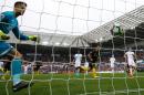 Swansea City goalkeeper Lukasz Fabianski (L) watches the ball hit the back of the net off a shot from Manchester City's Sergio Aguero (C) from the penalty spot