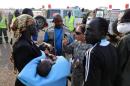 A handout photo released by the UNMISS shows a man carrying a baby as a group of wounded people are transported from Bor to Juba on December 22, 2103
