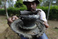 In this photo taken June 23, 2011, an archaeologist working along the flanks of Mount Tambora shows unearthed remnants of villages that were buried beneath up to 3 meters of ash. This artifact, used to grind spices, was found beneath an area that has since been turned into a coffee plantation. (AP Photo/KOMPAS Images, Fikria Hidayat) EDITORIAL USE ONLY