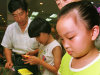 FILE - In this July 13, 1997 file photo, nine-year-old Zhu Ying tries out a Tamagotchi electronic pet at a Beijing department store. Bandai America Inc. and Sync Beatz Entertainment are hoping to revive the electronic pet craze of the 1990s with a new mobile app launching Thursday, Feb. 14, 2013, for Android devices. The app duplicates the egg-shaped plastic toy that became a must-own sensation after it was first released in 1996 in Japan. (AP Photo/Greg Baker, File)