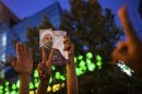 Supporters of moderate cleric Hassan Rohani hold a picture of him as they celebrate his victory in Iran's presidential election on a pedestrian bridge in Tehran