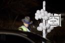 White balloons decorate the sign for the Sandy Hook Elementary School as a Connecticut State Trooper stands guard at the school's entrance, Saturday, Dec. 15, 2012, in Newtown, Conn. A gunman killed his mother at their home and later walked into Sandy Hook Elementary School Friday and opened fire, killing 26 people, including 20 children. (AP Photo/David Goldman)