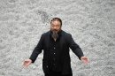 FILE - In this Monday, Oct. 11, 2010 file photo Chinese artist Ai Weiwei poses with some seeds from his art installation 'Sunflower Seeds' in London. Britain's Tate gallery says Monday March 5, 2012, it has bought a work by Chinese artist Ai Weiwei made up of 8 million ceramic sunflower seeds. The Tate said that 