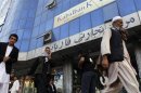 Afghan people walk past a Kabulbank branch in Kabul