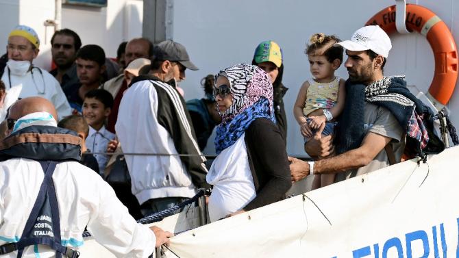 People with children  disembark from  the patrol vessel Fiorillo of the Italian Coast Guard in the port of Pozzallo after saving some 387 migrants in the Sicilian Channel, on August 7, 2015