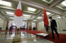 Staff from the Great Hall of the People prepare to remove Japanese and Chinese national flags after a welcome ceremony in Beijing