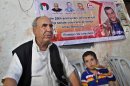 In this Friday, July 26, 2013, photo, Issa Masoud, 75, father of Omar, 40, who was arrested in May 1993 for killing an Israeli lawyer, listens during an interview at his family house at Shati Refugee Camp in Gaza City. Israel's Cabinet is to decide Sunday whether to release dozens of long-term Palestinian prisoners as part of U.S. Secretary of State John Kerry's attempt to restart Israeli-Palestinian talks after five years of diplomatic paralysis. Sitting next to Masoud is his 3-year-old grandson Mahmoud. (AP Photo/Adel Hana)