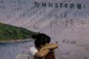 A woman, one of the relatives of Chinese passengers aboard the missing Malaysia Airlines flight MH370 takes a nap on a chair in front of a poster with writings for wishes for the passengers onboard the missing plane at a hotel in Beijing Sunday, March 30, 2014. Several dozen Chinese relatives of passengers on Flight 370 demanded Sunday that Malaysia apologize for its handling of the search for the missing plane and for the prime minister's statement saying it crashed into the southern Indian Ocean. (AP Photo/Andy Wong)
