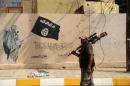 A member of the Iraqi security forces walks past a wall painted with the black flag commonly used by Islamic State militants in Shirqat