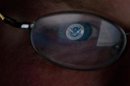 The logo of the U.S. Department of Homeland Security is reflected in the spectacles of an analyst working in a watch and warning center of a cyber security defense lab at the Idaho National Laboratory