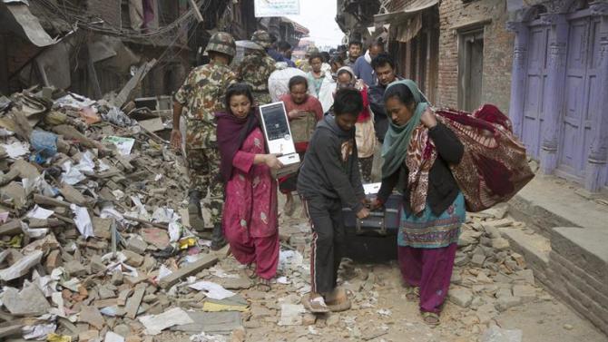 KAT64. Kathmandu (Nepal), 26/04/2015.- Local residents in search of safe accommodation carry essential belongings as they walk along a narrow road past a massively destroyed building 26 April 2015 - twenty four hours after a devastating earthquake that so far has taken the lives of more than 2,400 people. (Terremoto/sismo) EFE/EPA/Hemanta Shrestha