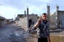 In this image taken from video obtained from the Ugarit News, which has been authenticated based on its contents and other AP reporting, A Free Syrian Army soldier flashes the victory sign, as damages caused by barrels fired from warplanes and rocket launchers is seen at background in Hama, Syria, on Monday, Jan. 28, 2013. (AP Photo/Ugarit News via AP video)