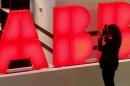 A woman takes pictures of the logo of Swiss power technology and automation group ABB in Zurich