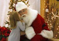 In this Wednesday, Nov. 30, 2011 photo, Santa, Cliff Snider, gets a kiss on the cheek from Bella Champion, 3, during a Christmas photo shoot at the "Beach Shack" in Emerald Isle, N.C. When Snider, who's been playing Santa since he was a teenager, gets a big-ticket request, he typically answers: "There's an awful lot of children asking for that this year. What else do you want?" (AP Photo/Tom Copeland)
