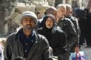 Residents wait to receive food aid distributed by UNRWA at the besieged al-Yarmouk camp