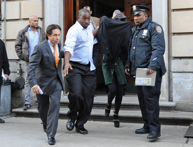 Lindsay Lohan, second from right, is escorted from the 10th Precinct police station, with her face shielded, Thursday, Nov. 29, 2012, in New York after being charged for allegedly striking a woman at a nightclub. Police say Lohan was arrested at 4 a.m. and charged with third-degree assault. They say she got into the argument with another woman at Club Avenue in Manhattan and struck the woman in face with her hand. (AP Photo/ Louis Lanzano)