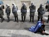 A protester wearing a Greek flag sits in front of riot police during a rally outside the Greek Parliament in Athens, Saturday, Feb. 11, 2012. The leaders of the two parties backing Greece's coalition government called on their deputies Saturday to back legislation that calls for harsh new austerity measures - essential if Greece is to get a new bailout deal worth euro 130 billion ($171.6 billion) and stave off bankruptcy. (AP Photo/Thanassis Stavrakis)
