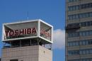 The logo of Toshiba Corp is seen as Window cleaners work on the company's headquarters in Tokyo
