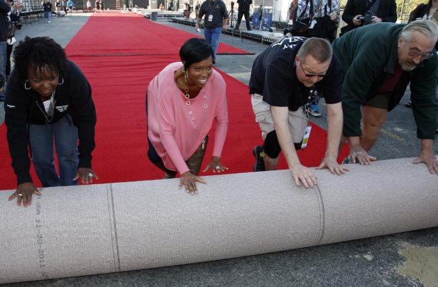 Actress Regina King, second left, poses with workers as they roll out the red carpet and setup for the SAG Awards at the Shrine Auditorium in Los Angeles on Saturday, Jan. 28, 2012. (AP Photo/Jason Redmond)